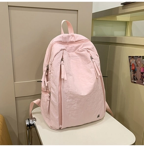 Detail view of light pink nylon backpack with textured fabric and vertical zipper pockets