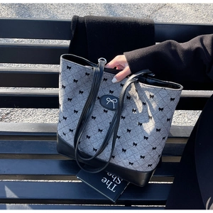 Détail d'un grand sac cabas gris matelassé avec motifs nœuds noirs et finitions cuir