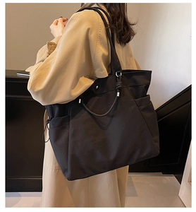 Detail view of large black tote bag with drawstring closure and stylish round metal handle