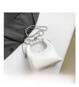 Détails du sac blanc avec des poignées en perles élégantes et une bandoulière en chaîne