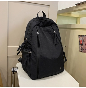 Detail view of black nylon backpack featuring multiple zippers and durable grab handle