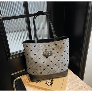 Gros plan du sac seau en jacquard gris avec broderie nœud et détails en cuir noir