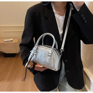 Detail of silver metallic Boston bag with double handles and adjustable crossbody strap