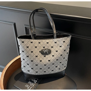 Détail du sac en tissu gris avec motifs de nœuds noirs sur fauteuil en cuir