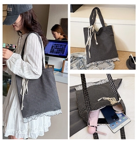 Detail of checkered tote bag with white lace trim and bow on the shoulder strap