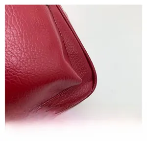 Detail of red pebbled leather backpack showing precise stitching and premium texture