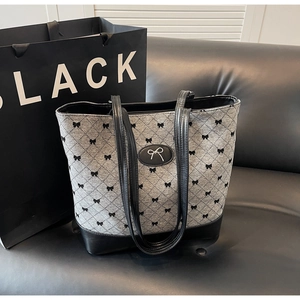 Détail du sac cabas en toile avec motifs de nœuds noirs et logo métallique élégant