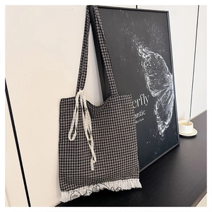 Detailed shot of black plaid tote bag with white lace trim and decorative ribbon bow