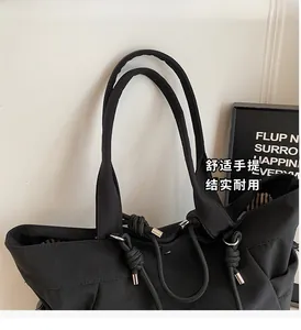 Detail of black nylon tote bag featuring drawstring metal closure and striped fabric lining