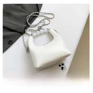 Gros plan d'un sac demi-lune blanc avec poignée en perles et détail de chaîne argentée