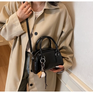Detail of black glossy bowling bag with baseball charm and long shoulder strap
