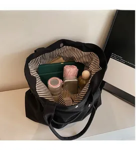 Detail view of spacious black tote interior with striped lining and magnetic closure