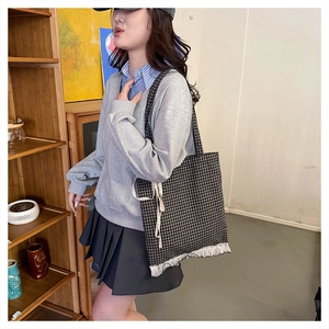 Close-up of plaid tote bag with delicate lace trim and ribbon detail on shoulder
