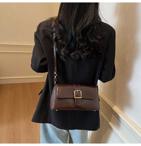 Détail arrière d'un sac baguette en cuir verni bordeaux foncé avec boucle dorée élégante