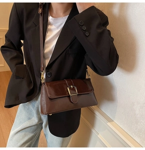 Détail d'un sac baguette vintage en cuir ciré marron foncé avec boucle métallique dorée