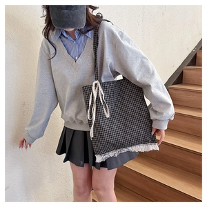 Detail of checkered canvas tote bag featuring ruffled lace trim and a cute ribbon bow