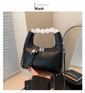 Détail d'un sac à main noir en similicuir avec poignée en perles et bandoulière chaîne