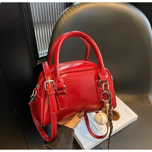 Detail of red patent leather bowling bag with vintage texture and baseball bag charm