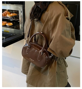 Sac à main marron brillant style vintage porté en bandoulière par un mannequin