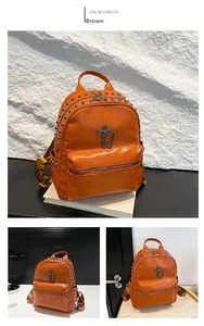Detail of orange pebble leather backpack with metal rivets and cross pendant accessory