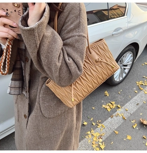 Macro detail of camel pleated matelassé leather tote bag with elegant knot accent
