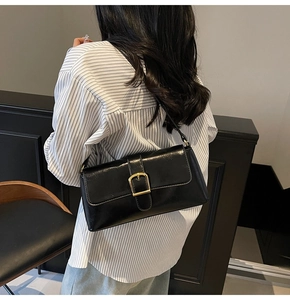 Vue latérale d'un sac baguette en cuir verni noir porté à l'épaule par un mannequin