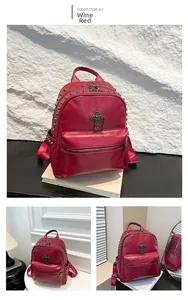 Close-up of wine red PU leather backpack with metallic rivets and cross pendant detail