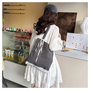 Lace-trimmed black and white checkered tote bag with elegant bow detail on shoulder strap