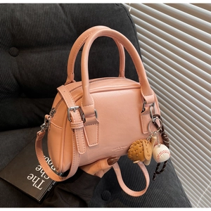 Detailed shot of pink PU leather bowling bag with baseball charm on grey background
