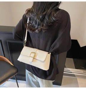 Détail du sac baguette crème avec finition brillante et boucle en métal doré chic
