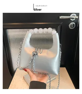 Détail du sac argenté avec poignée en perles acryliques et bandoulière en chaîne métallique