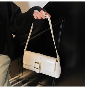 Détail du sac baguette blanc crème brillant avec une boucle carrée dorée élégante et chic