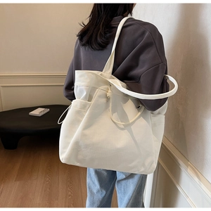 Minimalist cream canvas tote bag detail showing side pockets and drawstring closure design