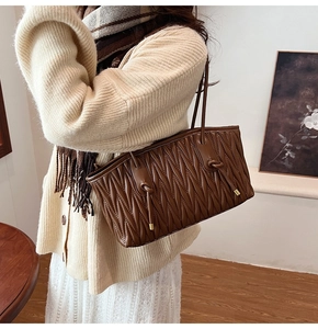 Detail showing the dark brown pleated matelassé texture and thin leather shoulder straps