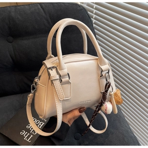 Close-up of cream PU leather Boston bag with baseball charm and ZSNS embossed logo