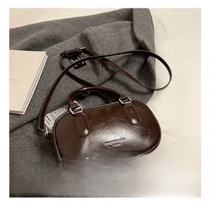 Détail du sac Boston en cuir brillant marron foncé avec logo de marque et finitions