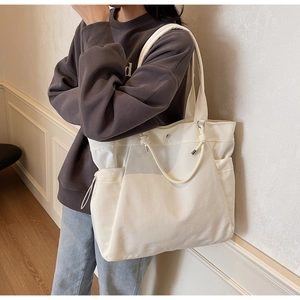 Macro shot of large beige canvas tote bag with functional side pockets and reinforced handles