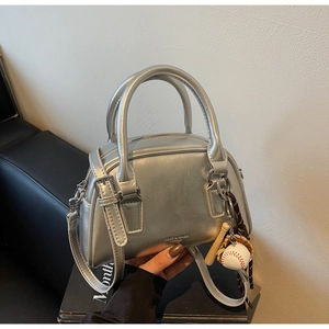 Detail of silver metallic Boston bag featuring baseball charms and adjustable strap