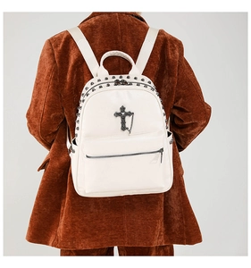 Close-up detail of white punk backpack with metal rivets and cross chain accessory