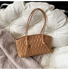 Detail view of caramel brown pleated tote bag with fine straps and gold metal accents