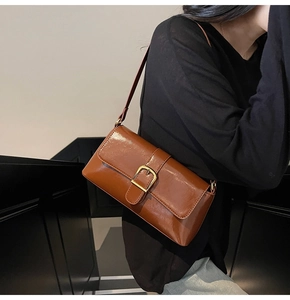 Gros plan détaillé montrant la texture du cuir ciré brillant de ce sac baguette marron