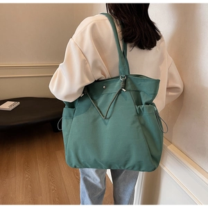 Deep green canvas tote bag detail showing side pocket and drawstring on female model