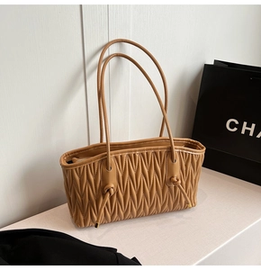 Close-up of pleated camel shoulder bag with V-shaped quilting and smooth zipper detail