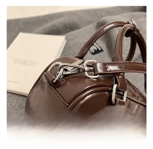 Détail du crochet métallique argenté sur le sac marron foncé en cuir synthétique