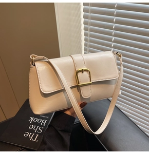 Détail d'un sac baguette blanc crème avec boucle en métal doré et finition cuir texturé