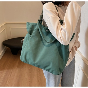 Close-up of a large green nylon tote bag showing textured fabric and knotted handle detail