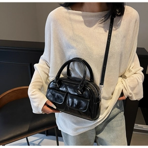 Detail view of glossy oil wax leather Boston bag with dual front flap pockets and strap