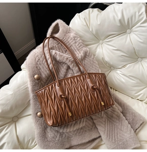Detail of a brown pleated tote bag featuring Matelassé quilting and gold metal accents