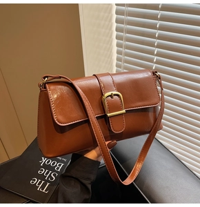 Détail du sac baguette marron caramel avec boucle dorée et texture en cuir lisse