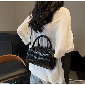 Close-up of black oil wax leather Boston bag featuring dual front pockets and glossy finish